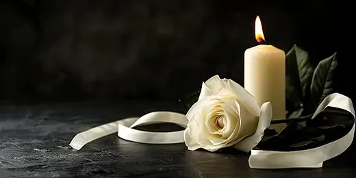 Rose blanche et bougie allumée sur fond sombre pour condoléances.